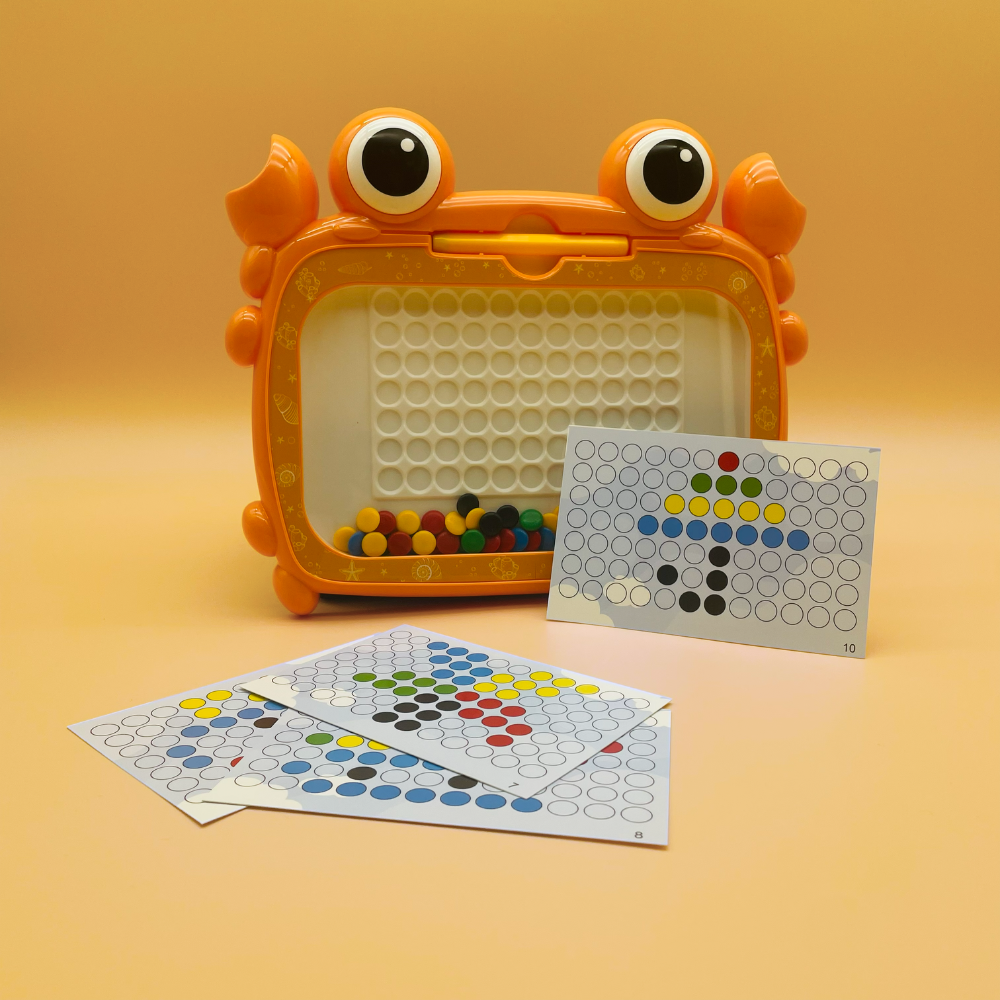 A children's toy color-sorting game set shaped like a cartoon crab, with an orange crab-shaped container holding small multicolored balls, plus several printed color-sorting cards placed in front on a warm beige studio background.