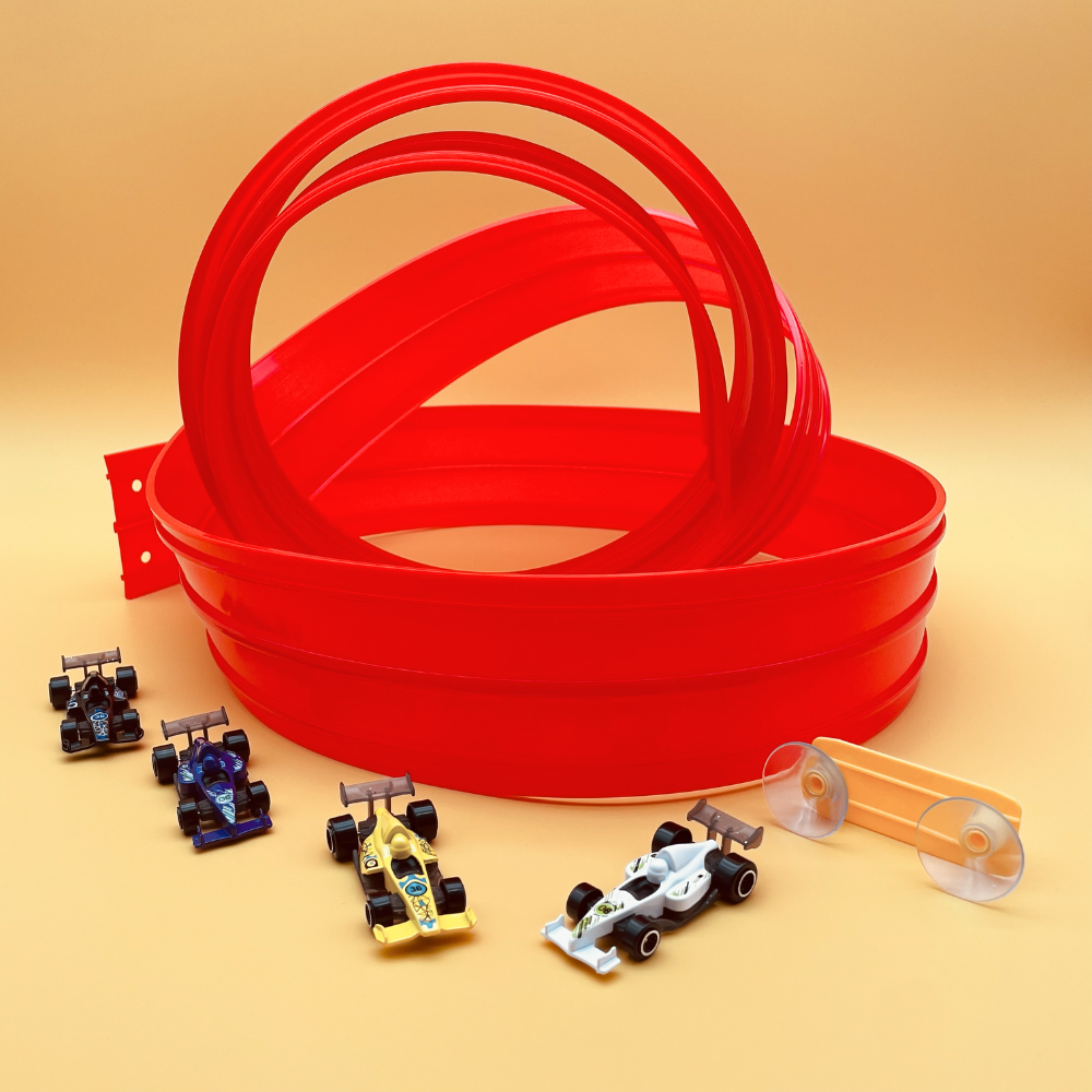 Red plastic loop track pieces arranged on a warm beige studio background, with four small toy race cars and two clear suction-cup accessories placed in front.